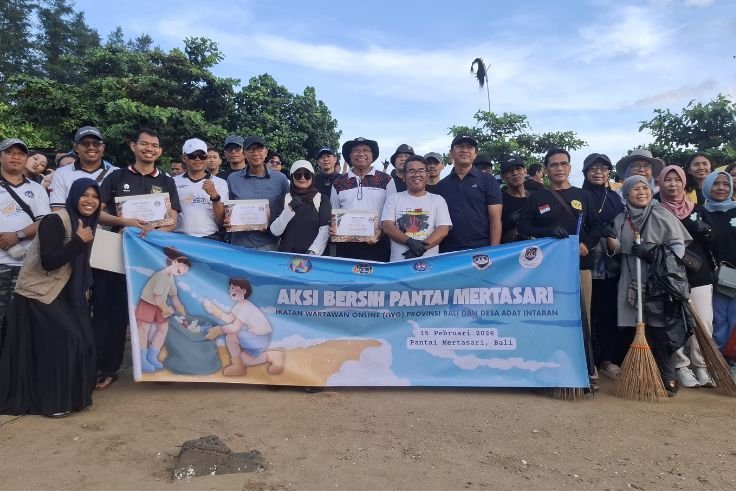 Members of Ikatan Wartawan Online Bali and cross-sector partners conduct a beach cleanup during an environmental action at Mertasari Beach, Denpasar, on Sunday (Feb 15, 2026).